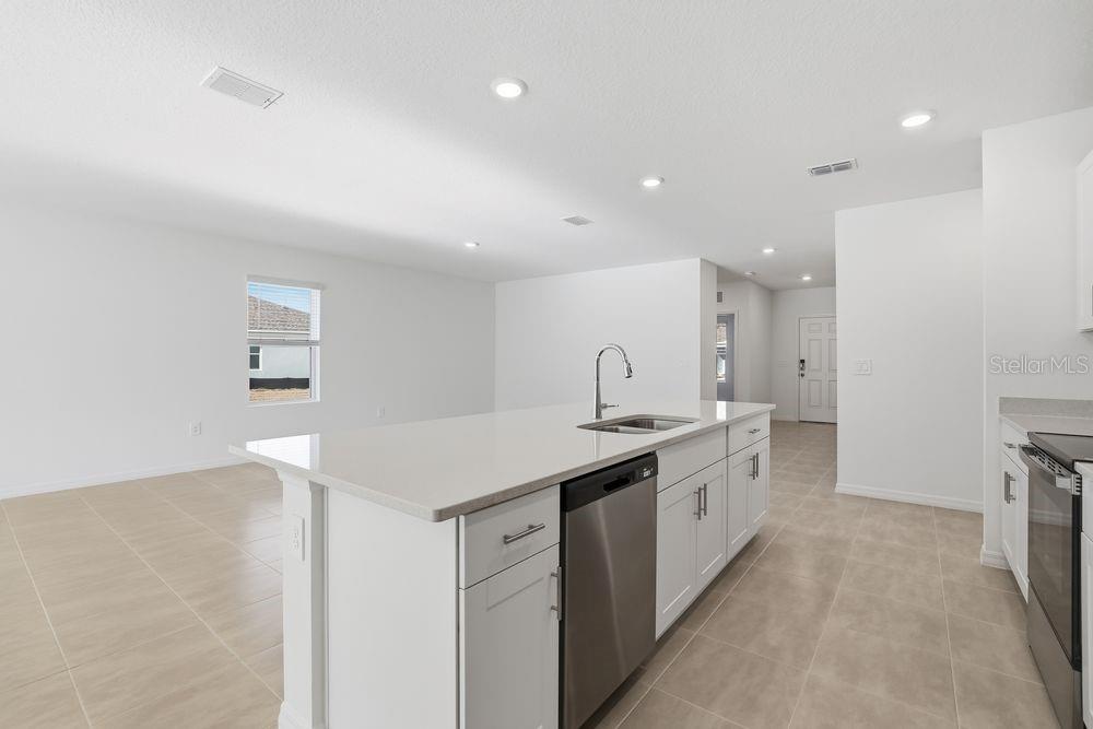 A kitchen island with a sink and dishwasher sits in a room with tiled floors — 13673 TROPICAL BREEZE WAY, HUDSON, FL