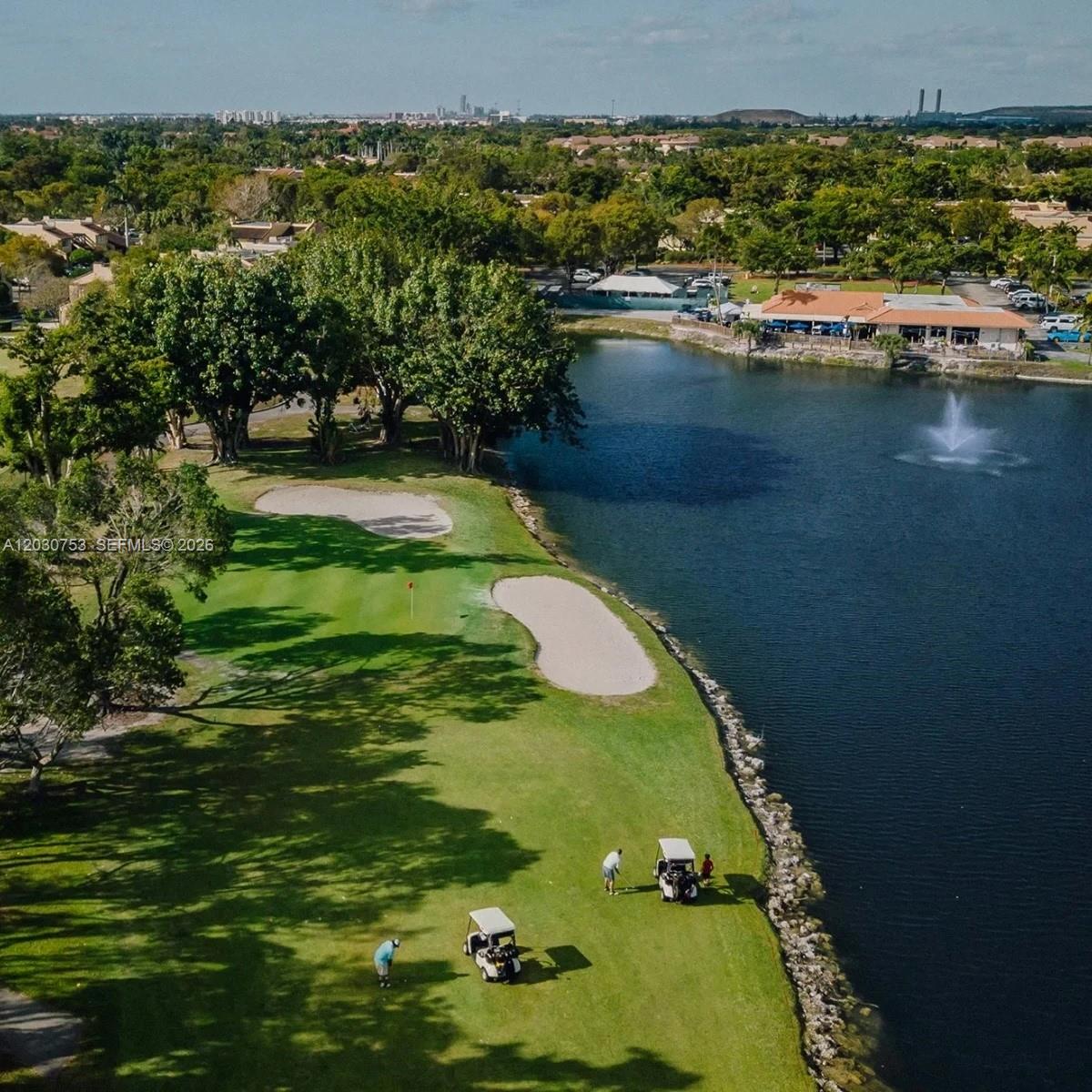 An aerial view of a golf course hole featuring a lake, sand traps, and golfers — 3932 Estepona Ave, Doral FL 33178, DORAL, FL