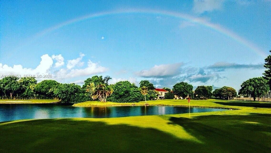 A golf course green overlooks a pond with a rainbow in the blue sky above — 3932 Estepona Ave, Doral FL 33178, DORAL, FL