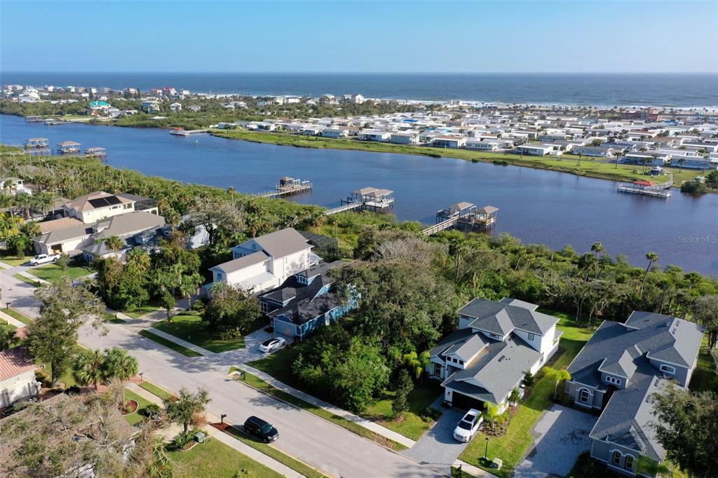 An aerial view shows houses near a waterway with docks and the ocean beyond — 41 S RIVERWALK DRIVE, PALM COAST, FL