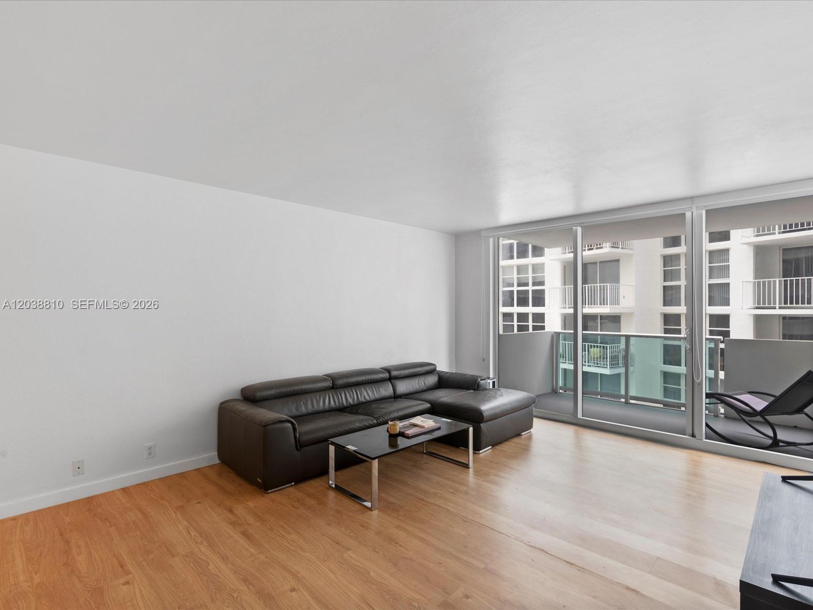A living room features a black leather sectional, a glass coffee table, and a balcony — 1200 West Ave # 823, Miami Beach FL 33139, MIAMI BEACH, FL