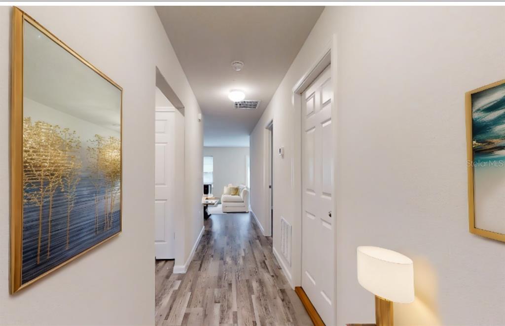 A hallway with wood-look flooring leads toward a living area with white walls and doors — 18 SECOND PATH UNIT A & B, PALM COAST, FL