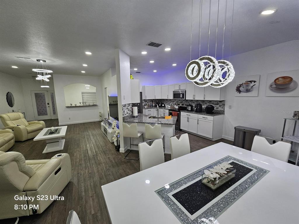 An open-concept kitchen and dining area features white cabinetry, granite countertops, and modern pendant lighting — 2256 TOWERING OAKS CIRCLE, SEFFNER, FL