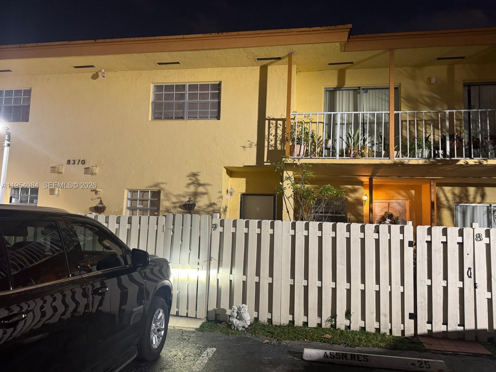 A two-story yellow apartment building with a white picket fence and a parked vehicle — 8370 SW 154th Ave # 9, Miami FL 33193, MIAMI, FL