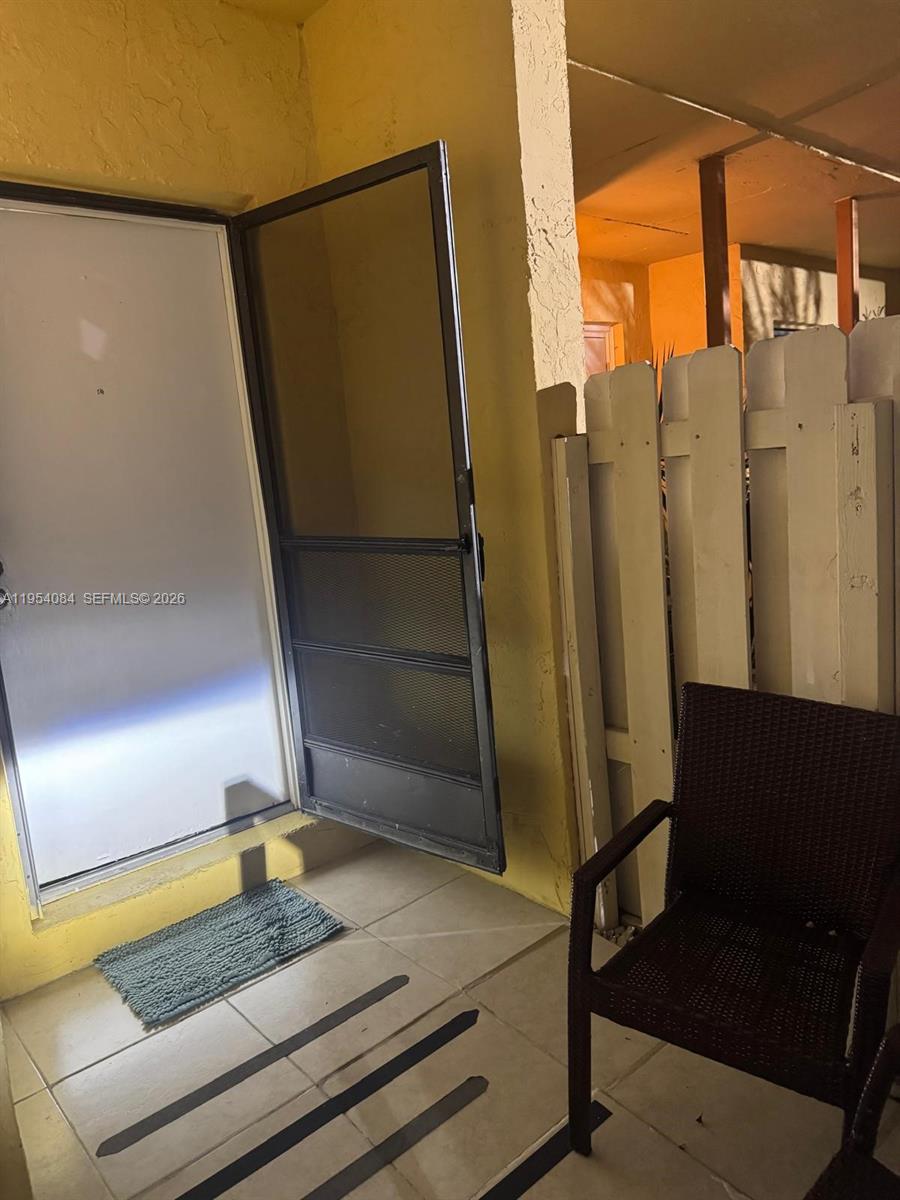 A patio area features a white door with a screen door, tile flooring, and a chair — 8370 SW 154th Ave # 9, Miami FL 33193, MIAMI, FL
