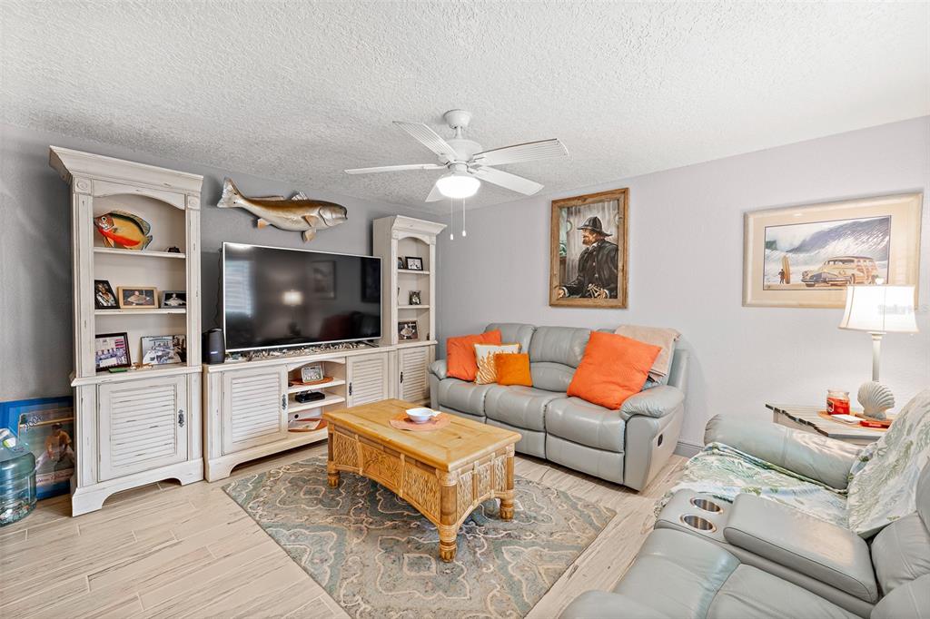 A living room features light tile floors, a gray sofa with orange pillows, and a television — 8767 LIVE OAK COURT, CAPE CANAVERAL, FL