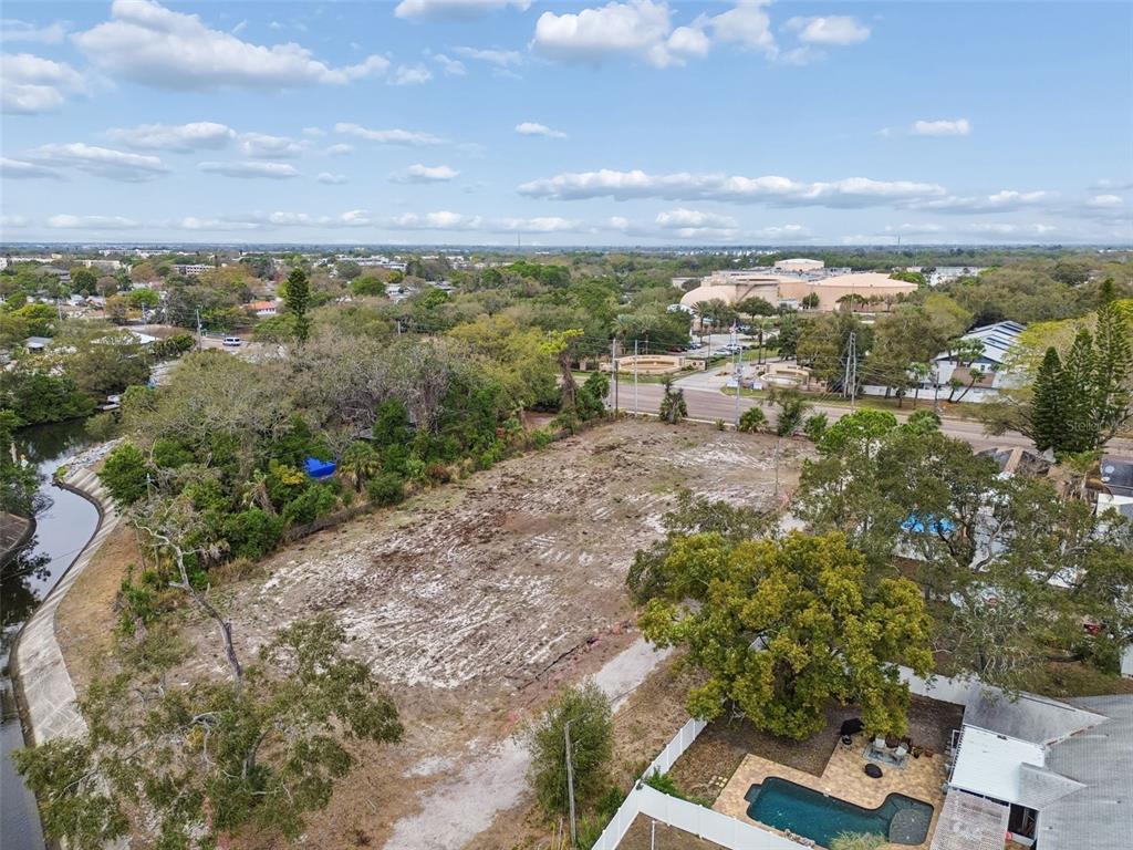 An aerial view shows a cleared, vacant lot bordered by trees, a canal, and houses — 5306 73RD WAY N, ST PETERSBURG, FL