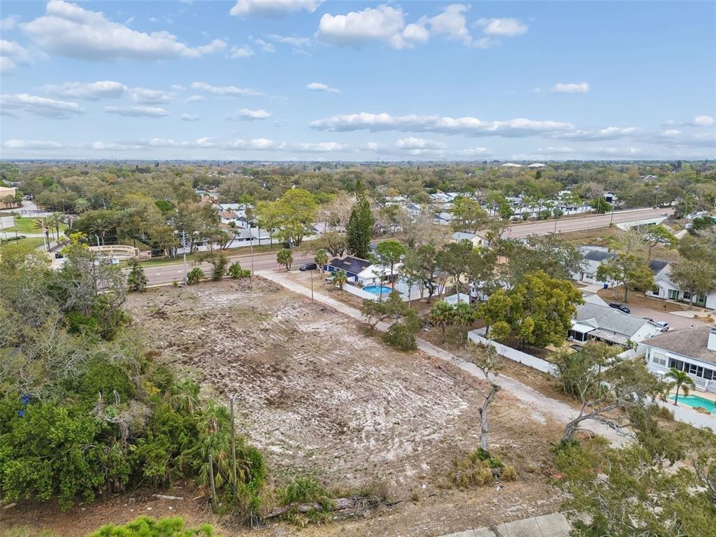 An aerial view shows a vacant, cleared rectangular lot bordered by trees and residential houses — 5306 73RD WAY N, ST PETERSBURG, FL