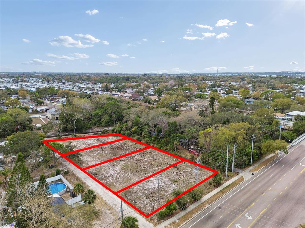 An aerial view shows three adjacent vacant rectangular lots bordered by a road and trees — 5306 73RD WAY N, ST PETERSBURG, FL
