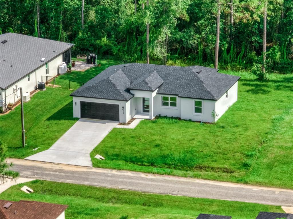 An aerial view of a single-story white house with a dark roof and two-car garage — 8725 CAPILLA STREET, SEBRING, FL