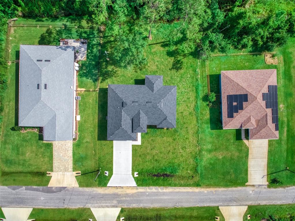An aerial view shows three detached houses with driveways and lawns along a paved road — 8725 CAPILLA STREET, SEBRING, FL