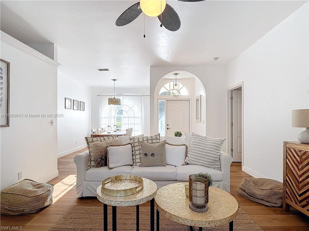 A living room features a white sofa, two round coffee tables, and wood flooring — 4991 Brixton Ct, Naples FL 34104, NAPLES, FL