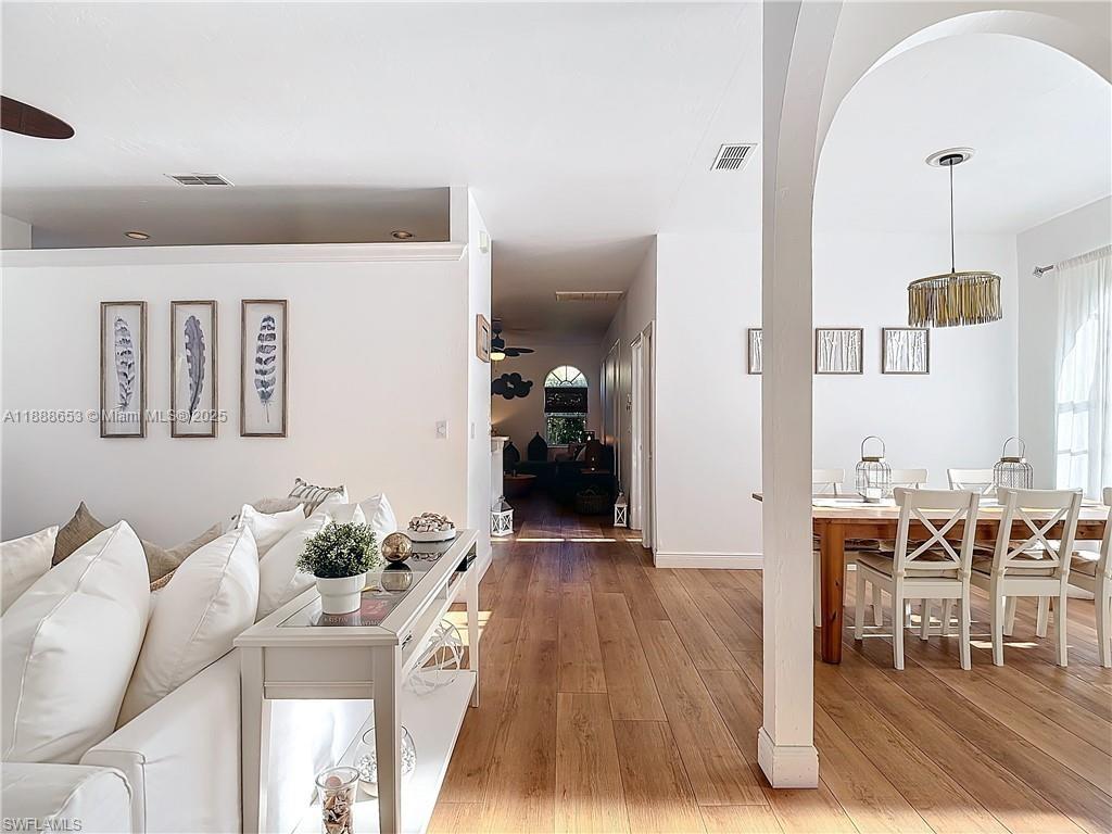 A bright living and dining area features white walls, wood flooring, and an arched entryway — 4991 Brixton Ct, Naples FL 34104, NAPLES, FL