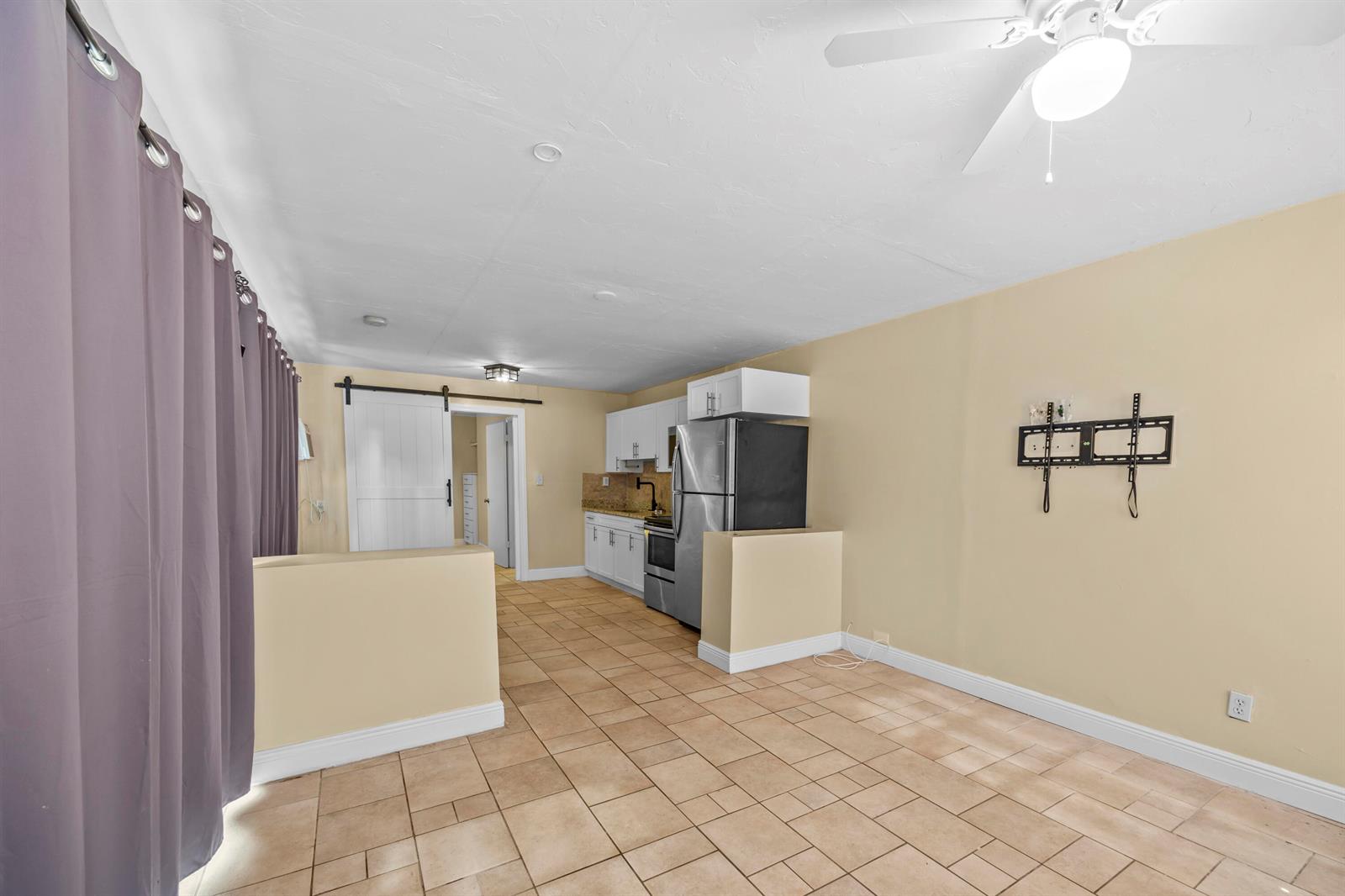 A kitchen with stainless steel appliances and tile flooring opens into a living area — 120 Pleasant Place # 1, Palm Springs FL 33461, PALM SPRINGS, FL