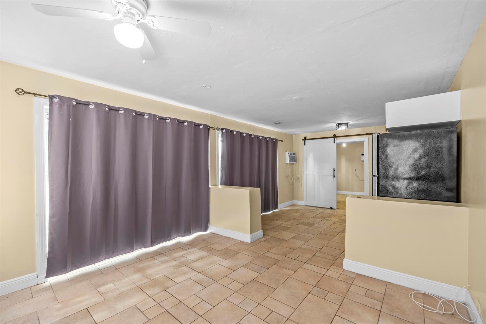 A room with tan tile floors, beige walls, purple curtains, and a white barn door — 120 Pleasant Place # 1, Palm Springs FL 33461, PALM SPRINGS, FL