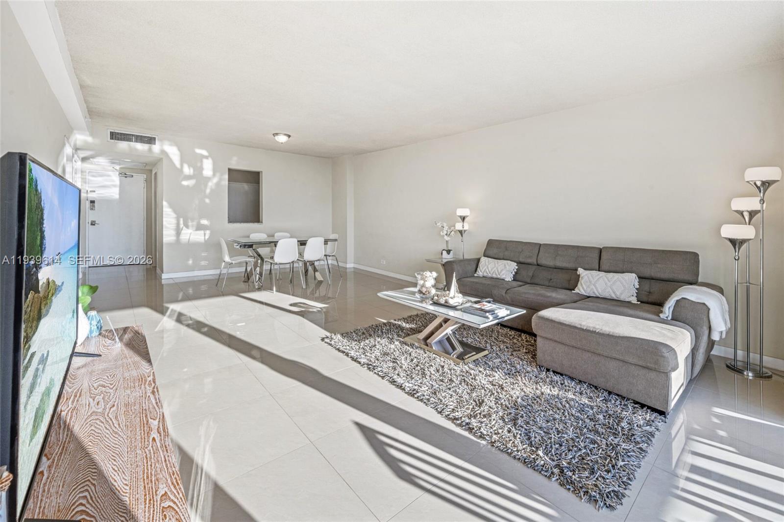 A living room features a gray sectional sofa, a shag rug, and a dining area — 5601 Collins Ave # 1618, Miami Beach FL 33140, MIAMI BEACH, FL