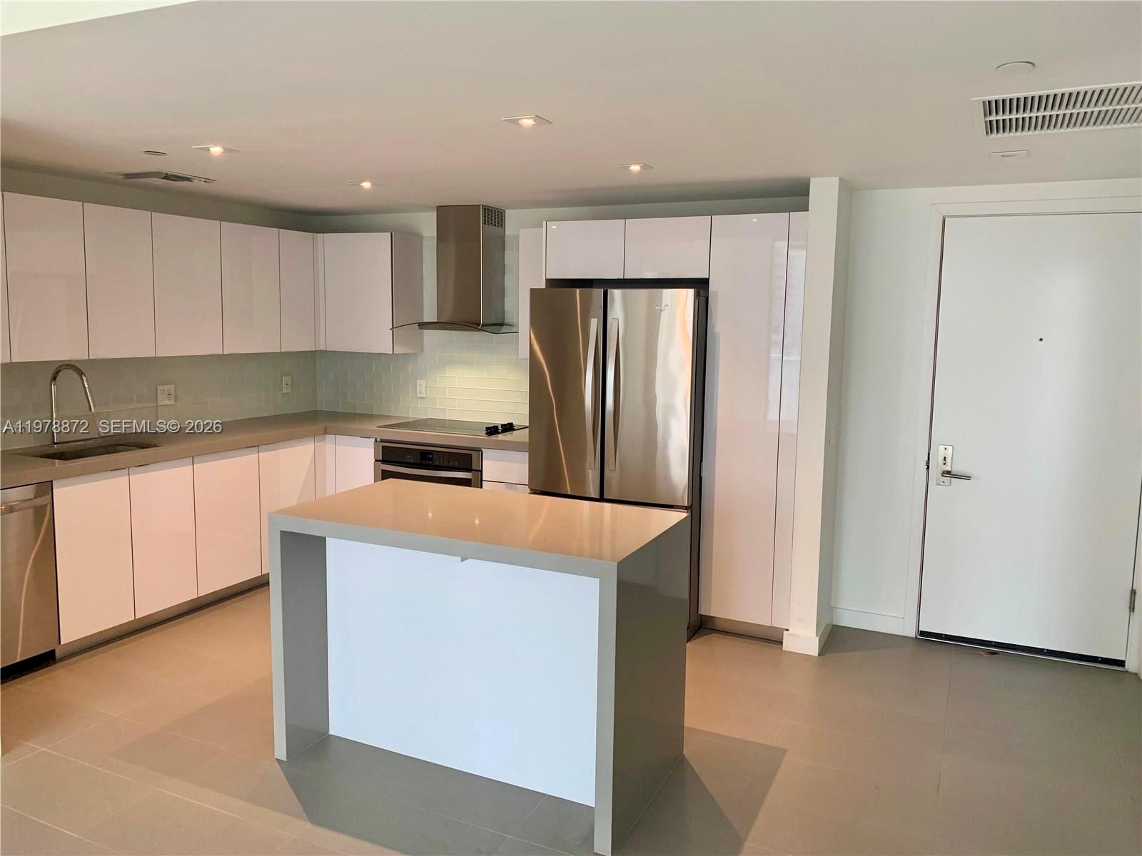 A modern kitchen features white cabinets, stainless steel appliances, and a gray central island — 1600 NE 1st Ave # 1008, Miami FL 33132, MIAMI, FL