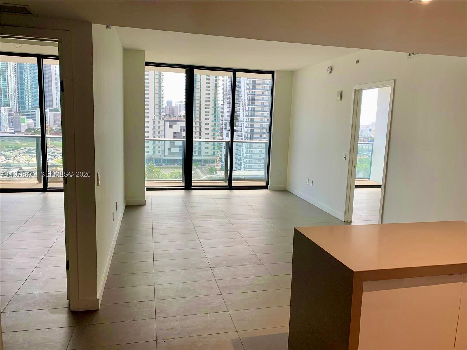 A modern living area features large floor-to-ceiling windows, light tile flooring, and city views — 1600 NE 1st Ave # 1008, Miami FL 33132, MIAMI, FL