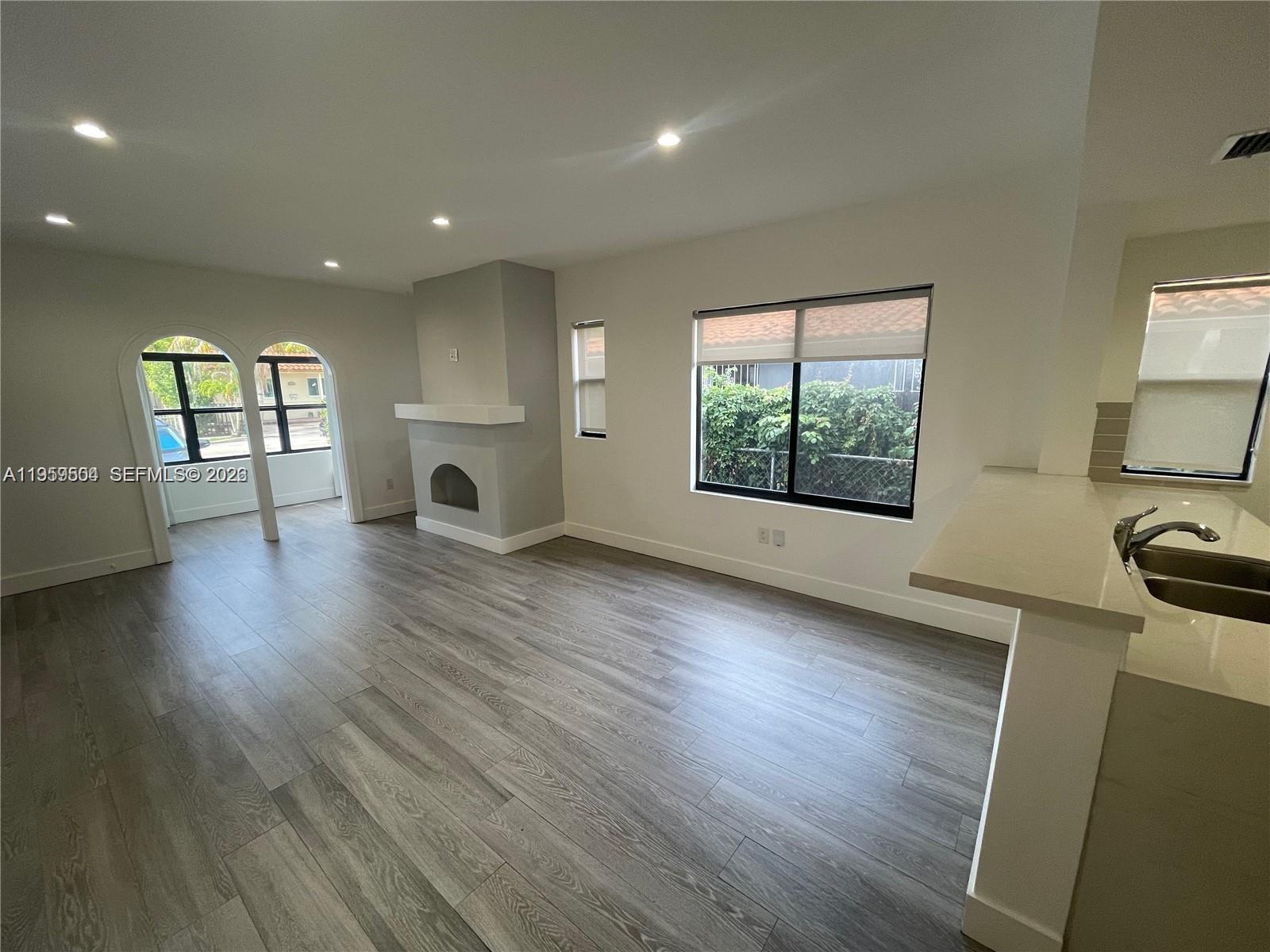 A living room features light wood-look flooring, a fireplace, and arched doorways leading outside — 1637 SW 10th St # 2, Miami FL 33135, MIAMI, FL