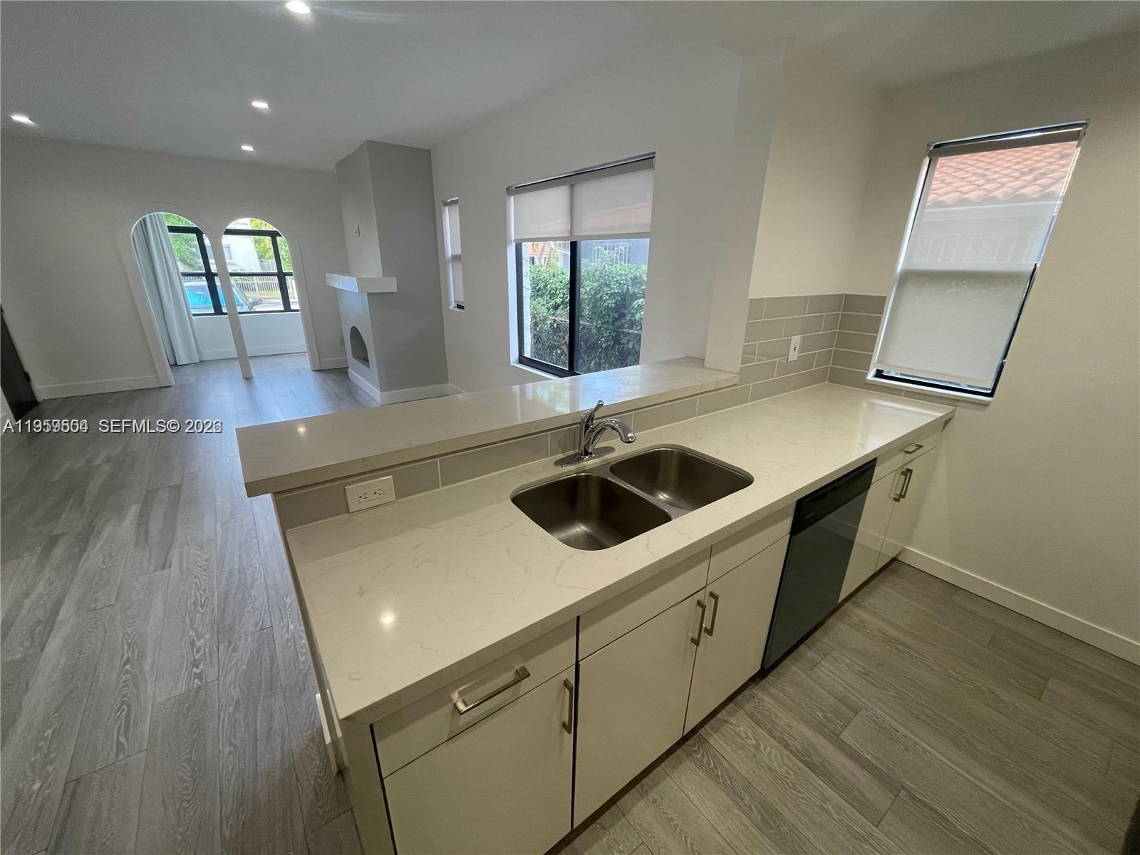 A kitchen with light-colored cabinets, quartz countertops, and a double sink overlooks a living area — 1637 SW 10th St # 2, Miami FL 33135, MIAMI, FL