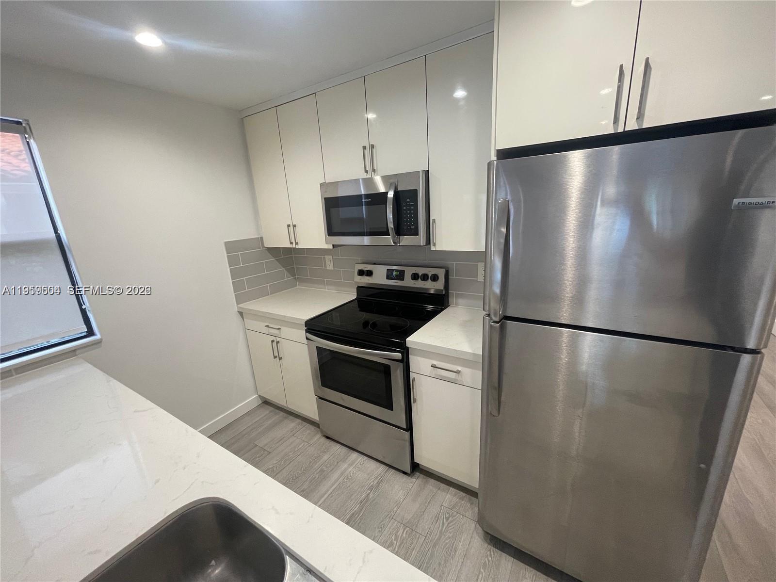 A kitchen features white cabinets, stainless steel appliances, a gray tile backsplash, and quartz countertops — 1637 SW 10th St # 2, Miami FL 33135, MIAMI, FL