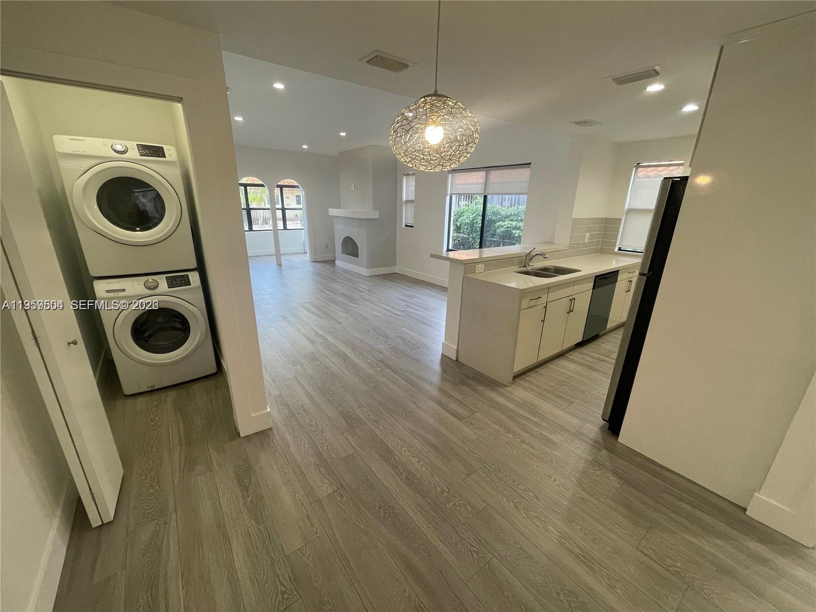 A kitchen with light cabinets and a laundry closet opens into a living area — 1637 SW 10th St # 2, Miami FL 33135, MIAMI, FL