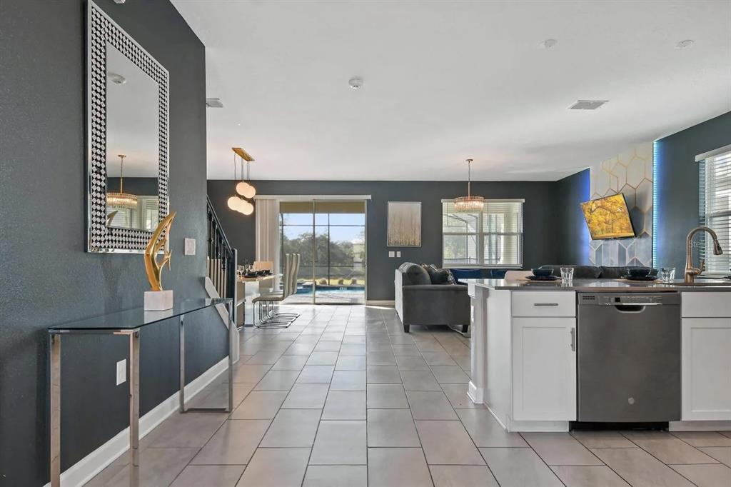 An open-concept kitchen and living area features dark gray walls, tile flooring, and a pool — 2721 BOOKMARK DRIVE, KISSIMMEE, FL
