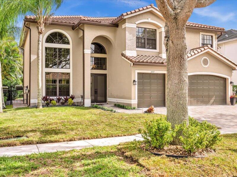 A two-story beige house with a tile roof, arched windows, and a three-car garage — 11737 Preservation Lane, Boca Raton FL 33498, BOCA RATON, FL