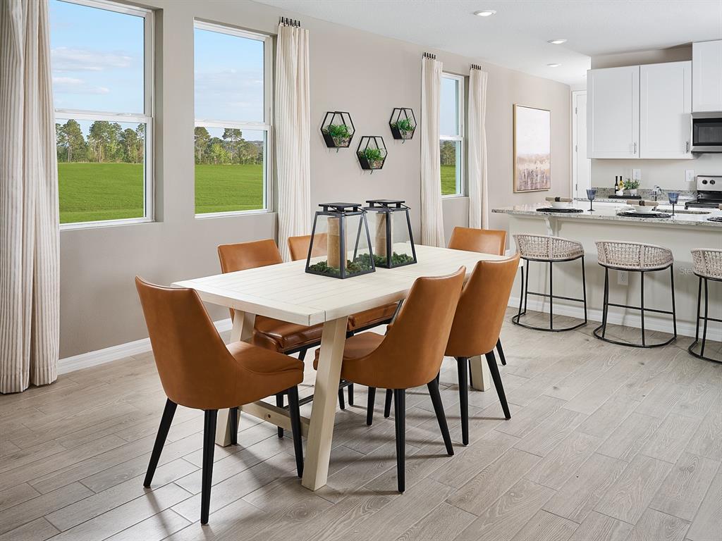 A dining area with a white table, tan chairs, and a kitchen island with stools — 1518 BREKEY WAY, ZEPHYRHILLS, FL