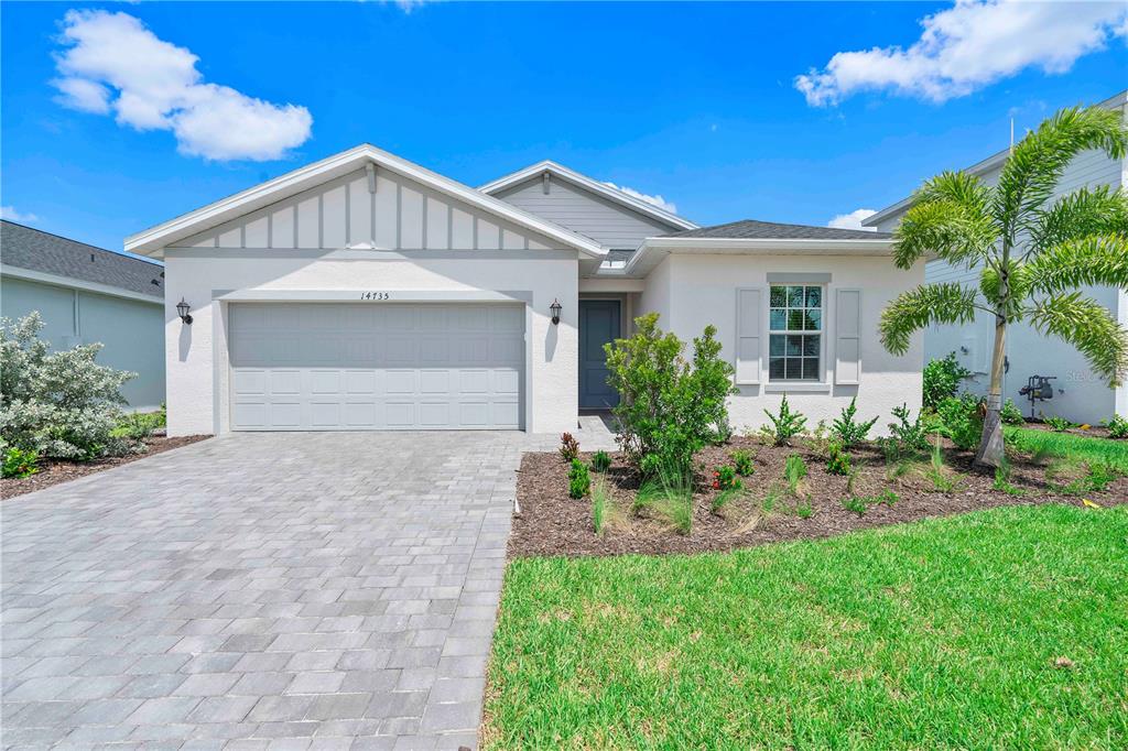 A single-story house with a two-car garage, light-colored stucco exterior, and a paved driveway — 14735 BLUEWATER ROAD, PUNTA GORDA, FL