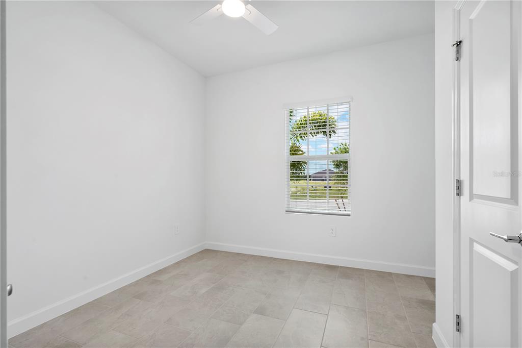 A small, empty room with white walls, tile flooring, a ceiling fan, and a window — 14735 BLUEWATER ROAD, PUNTA GORDA, FL