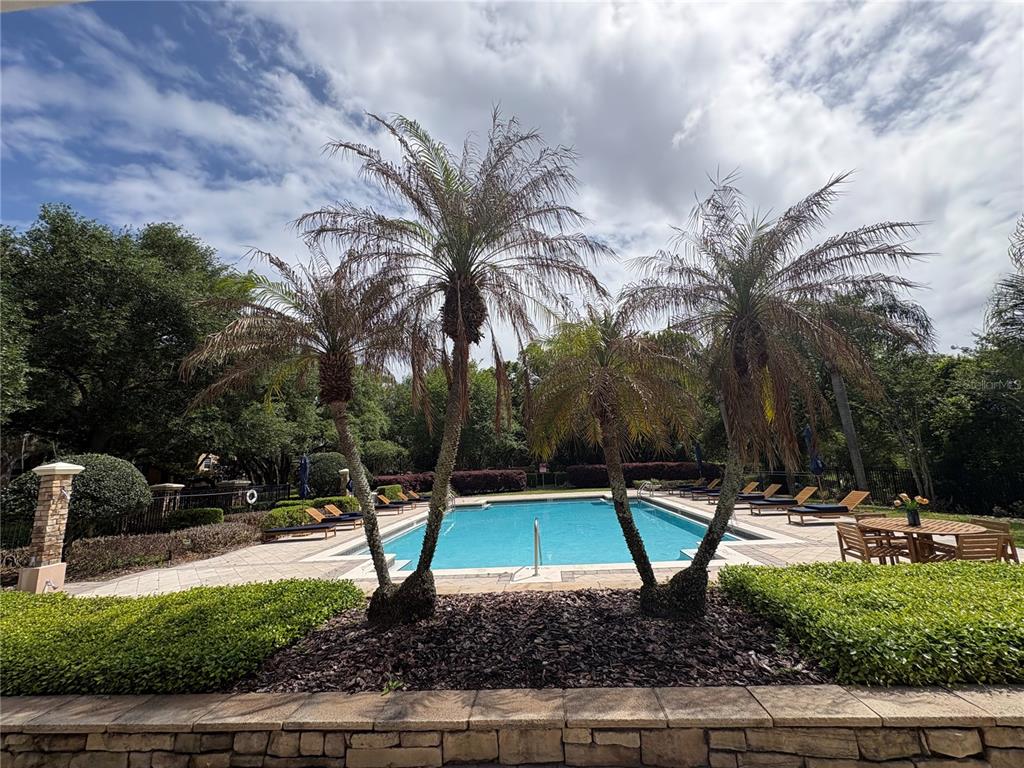 A swimming pool is surrounded by palm trees, lounge chairs, and a stone patio — 3190 DANTE DRIVE UNIT 307, ORLANDO, FL