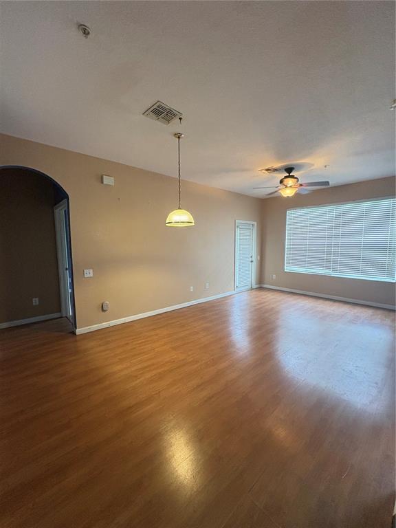 An empty room features light-colored walls, wood-look flooring, a ceiling fan, and a pendant light — 3190 DANTE DRIVE UNIT 307, ORLANDO, FL