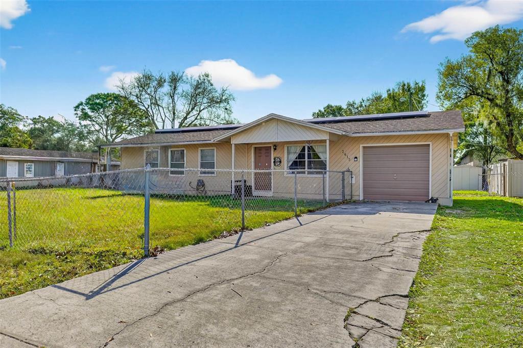 A single-story house with tan siding, a concrete driveway, and a chain-link fenced yard — 2613 FOWLER AVENUE, AUBURNDALE, FL