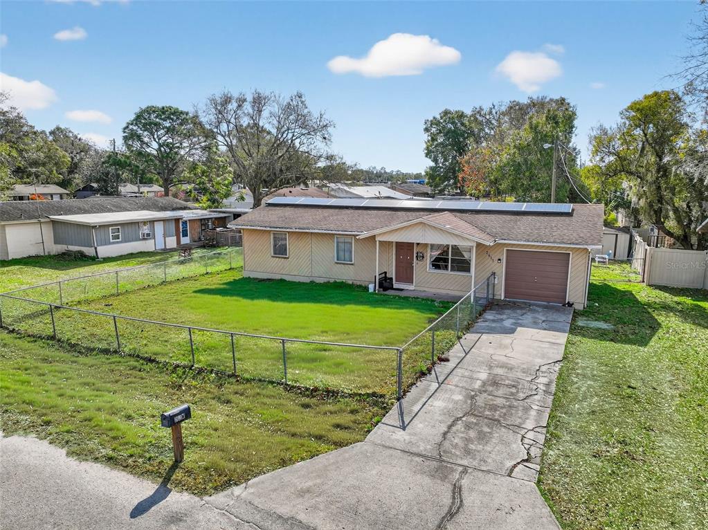 A single-story house with a fenced yard, solar panels, and a concrete driveway — 2613 FOWLER AVENUE, AUBURNDALE, FL