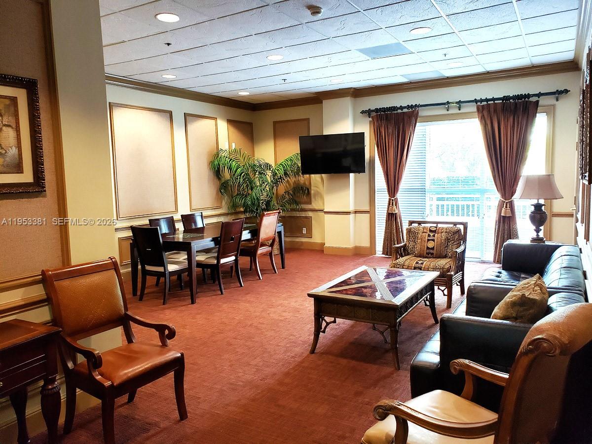 A carpeted living and dining area features a television, leather sofa, and large windows — 2665 SW 37th Ave # 611, Miami FL 33133, MIAMI, FL