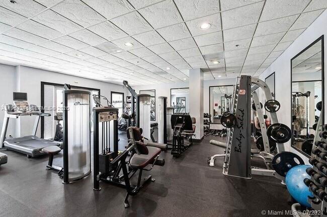 A gym features various weight machines, treadmills, mirrors, and a blue exercise ball — 2665 SW 37th Ave # 611, Miami FL 33133, MIAMI, FL
