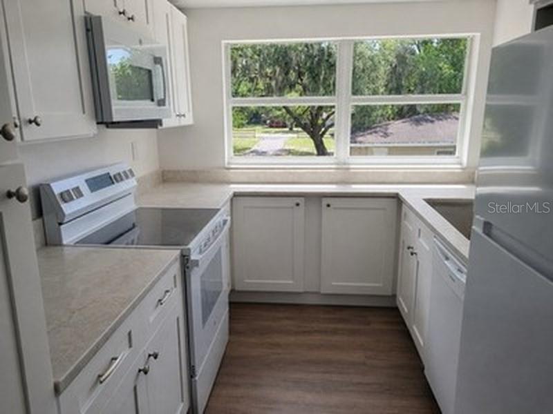 A kitchen features white cabinets, light countertops, stainless steel appliances, and a window over the sink — 3425 HOLLAND DRIVE, BRANDON, FL