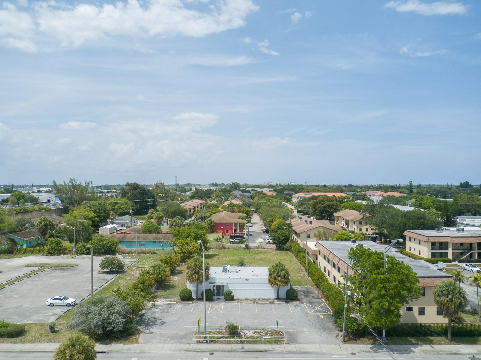 An aerial view shows a small white commercial building with a parking lot and surrounding trees — 1744 Lake Worth Road, FL 33460, FL