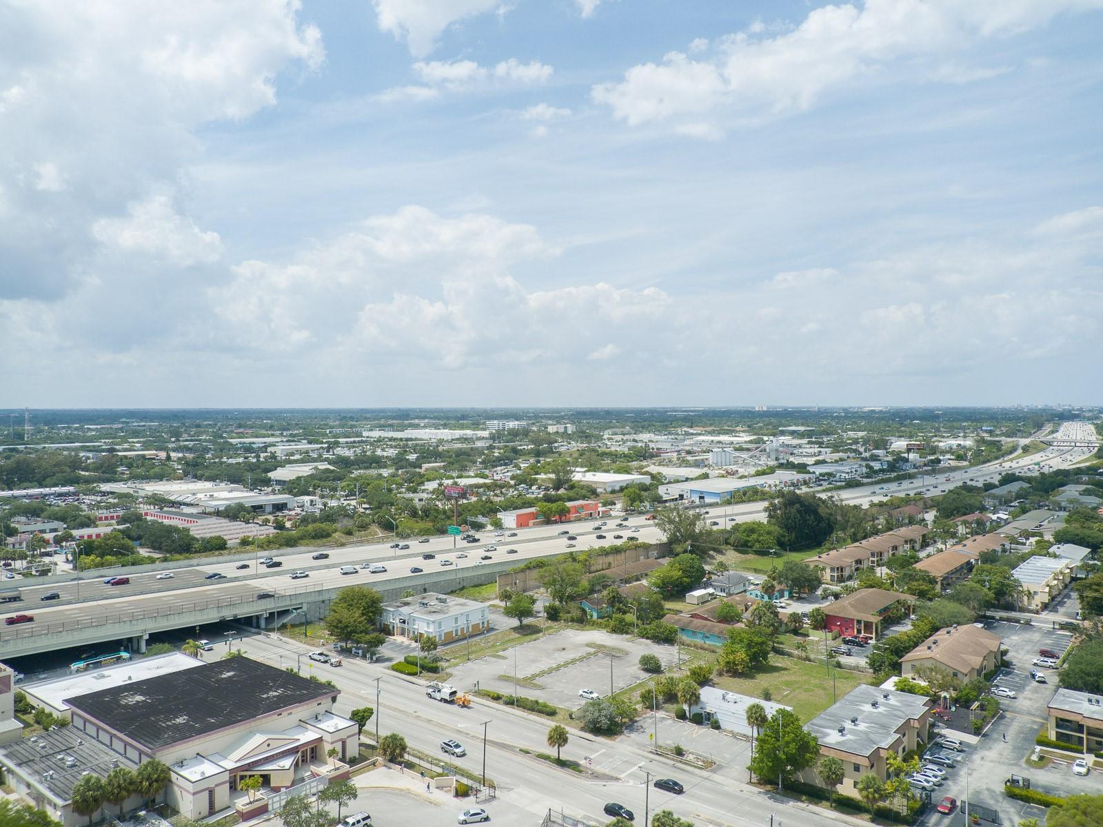 An aerial view shows a multi-lane highway crossing over a suburban area with commercial buildings — 1744 Lake Worth Road, FL 33460, FL