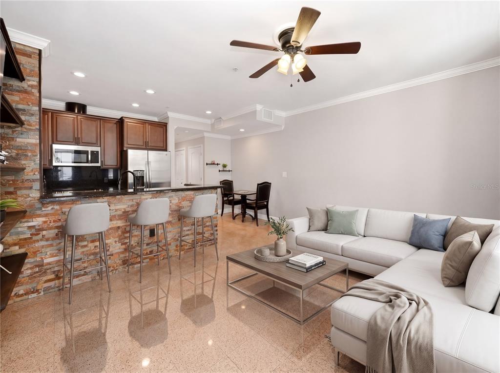 An open-concept living room and kitchen featuring stone accents, a breakfast bar, and tile flooring — 709 BLOOM STREET UNIT 160, CELEBRATION, FL