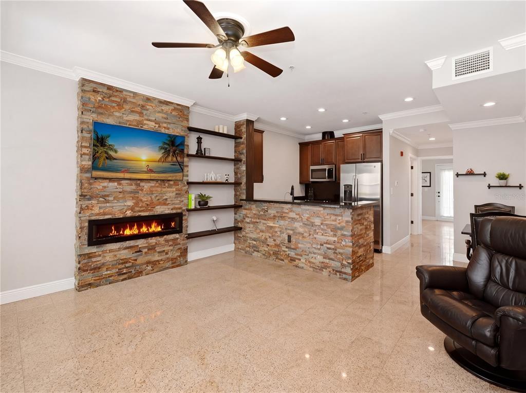 A living room and kitchen area features a stone fireplace wall, tile flooring, and cabinetry — 709 BLOOM STREET UNIT 160, CELEBRATION, FL