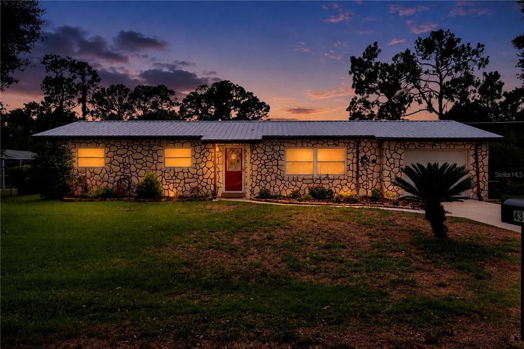 A single-story house with a stone facade and a metal roof at dusk — 4314 LARK DRIVE, DOVER, FL
