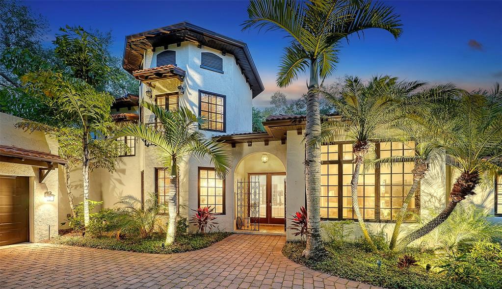 A two-story stucco home with a turret, arched entryway, and palm trees at dusk — 922 INDIAN BEACH DRIVE, SARASOTA, FL