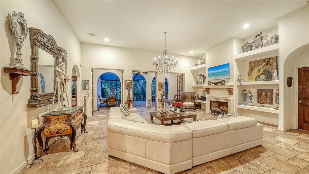 A spacious living room features a large sectional sofa, stone flooring, a fireplace, and chandelier — 922 INDIAN BEACH DRIVE, SARASOTA, FL