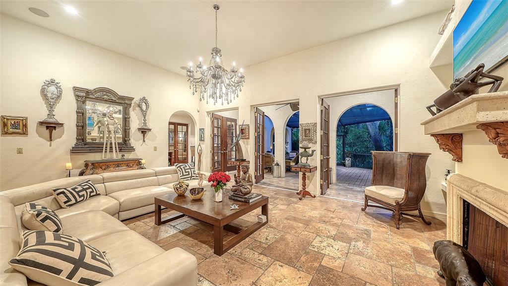A living room features a large sectional sofa, a crystal chandelier, and stone tile flooring — 922 INDIAN BEACH DRIVE, SARASOTA, FL