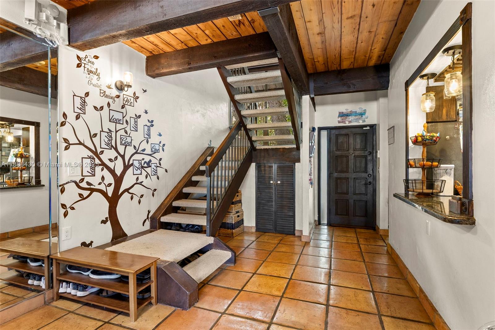 An entryway features a staircase, a tree wall decal, tile flooring, and exposed wood beams — 19440 NE 26th Ave # 53B, Miami FL 33180, MIAMI, FL