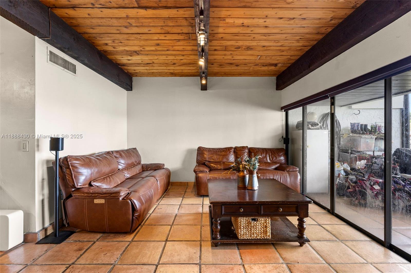 A living room features a wood-plank ceiling, tile flooring, and two brown leather sofas — 19440 NE 26th Ave # 53B, Miami FL 33180, MIAMI, FL