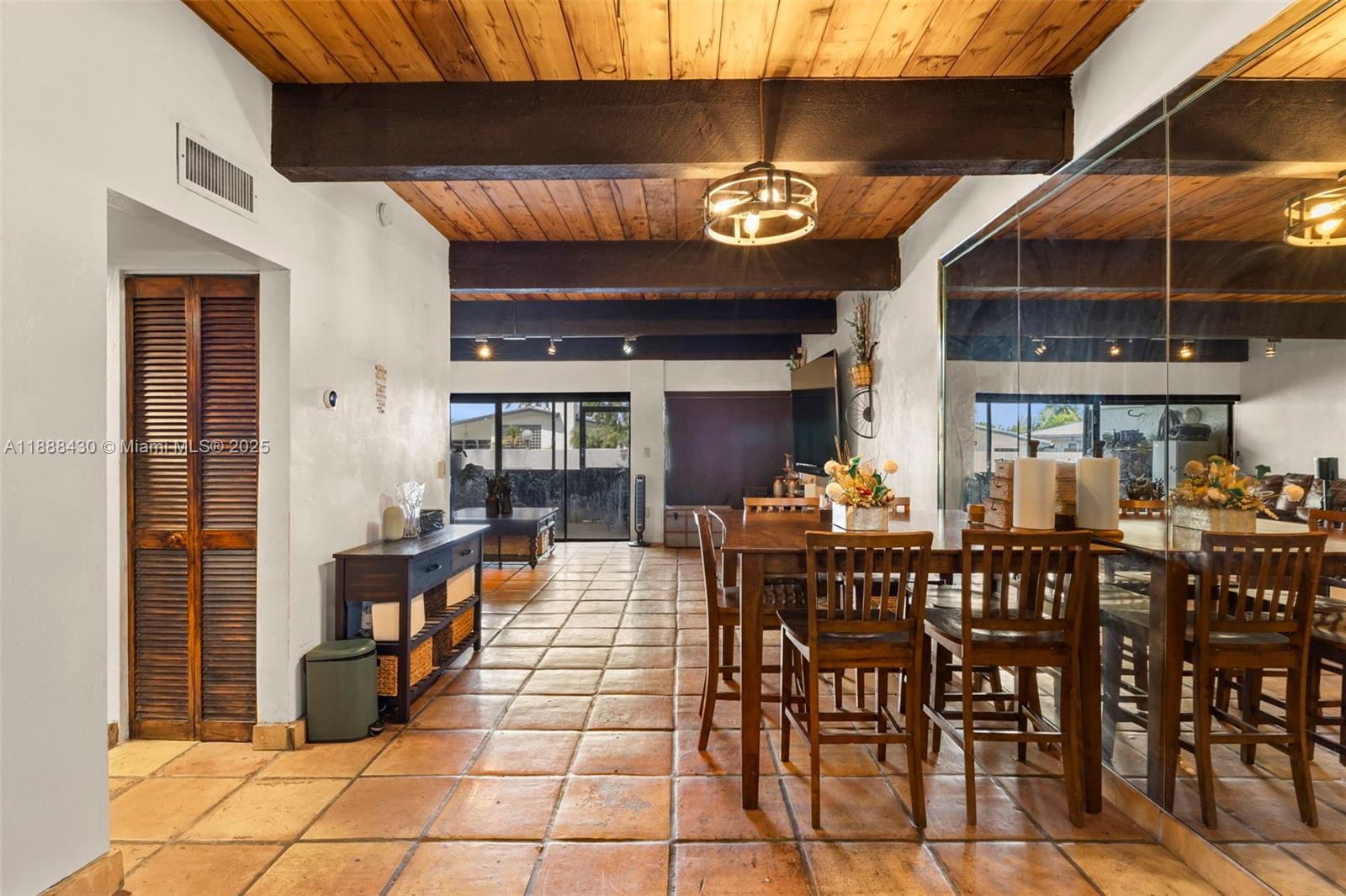 A dining area with terracotta tile floors, wood-beamed ceilings, and a large mirrored wall — 19440 NE 26th Ave # 53B, Miami FL 33180, MIAMI, FL