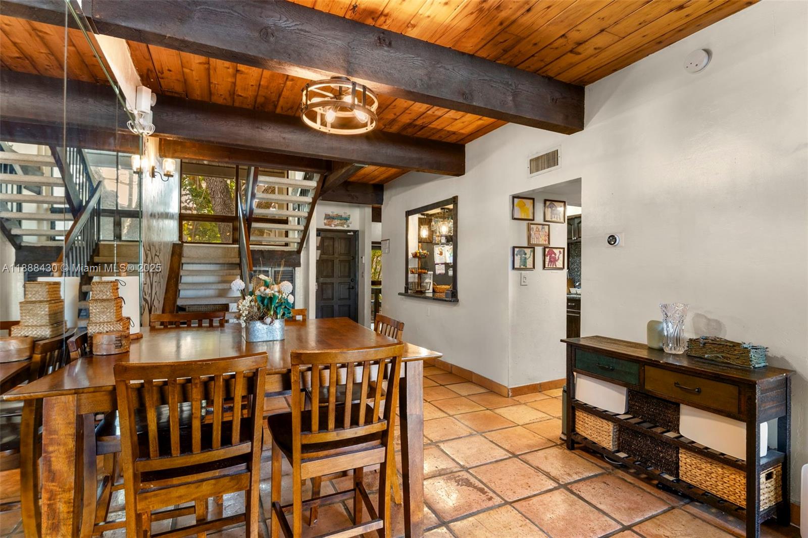 A dining area features a wooden table, exposed ceiling beams, and terracotta tile flooring — 19440 NE 26th Ave # 53B, Miami FL 33180, MIAMI, FL